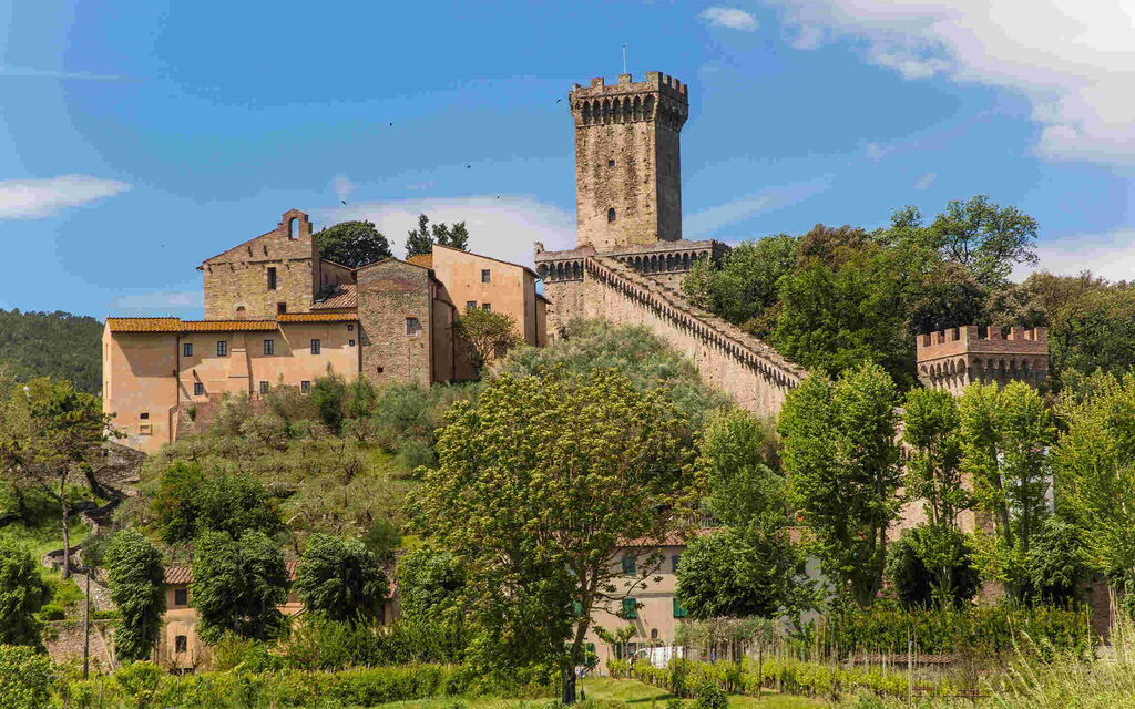 Medieval festival in the historic village of Vicopisano with historical reenactors, medieval flags and the Brunelleschi Fortress overlooking the celebrations.