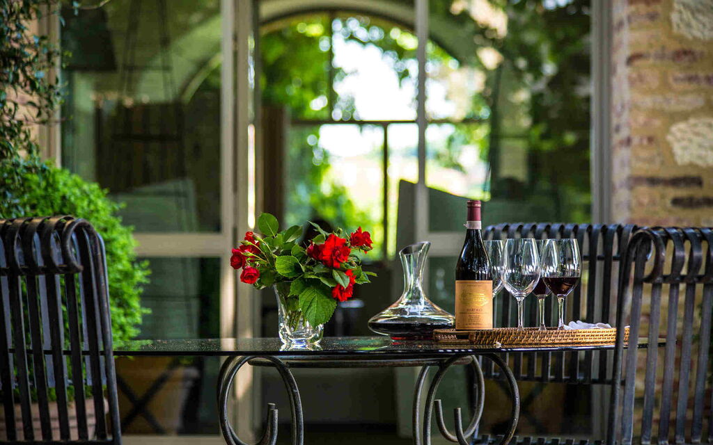 Glass of red wine, Montecarlo wine bottle and grapes overlooking the Tuscan hills near Lucca