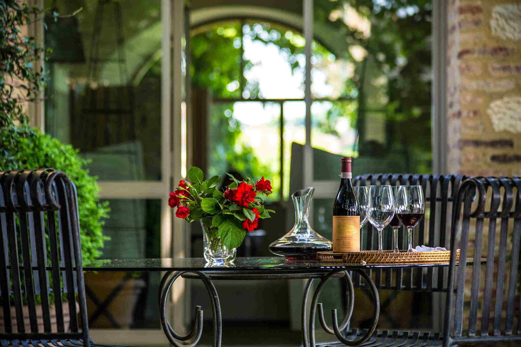 Glass of red wine, Montecarlo wine bottle and grapes overlooking the Tuscan hills near Lucca